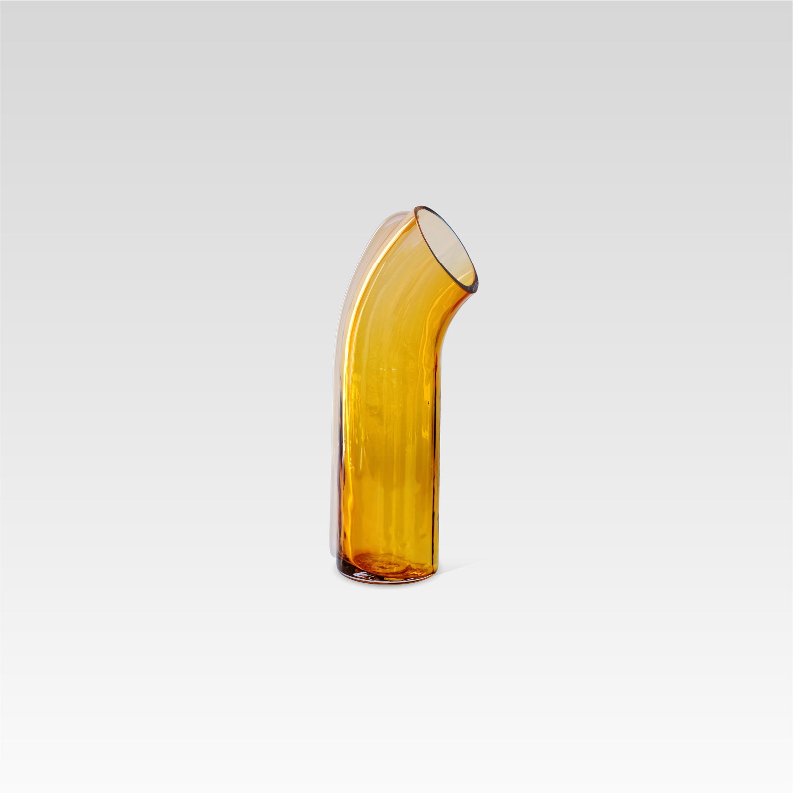 Curved amber coloured glass vase with a pale apricot strip of glass on the back of it, positioned on a white background