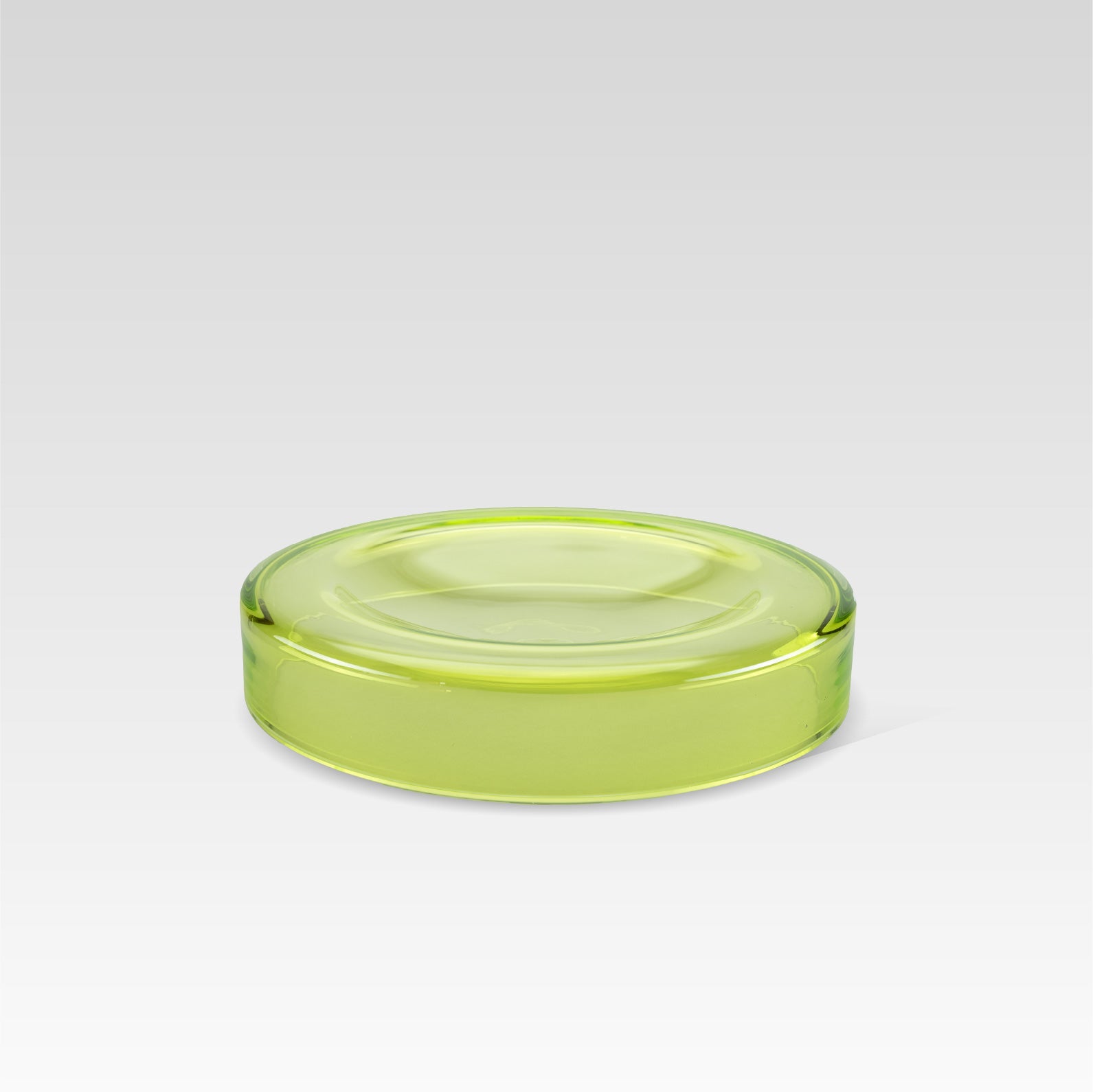 Handmade green glass bowl with a smooth surface and a subtle shine, designed to make objects appear to float on its surface