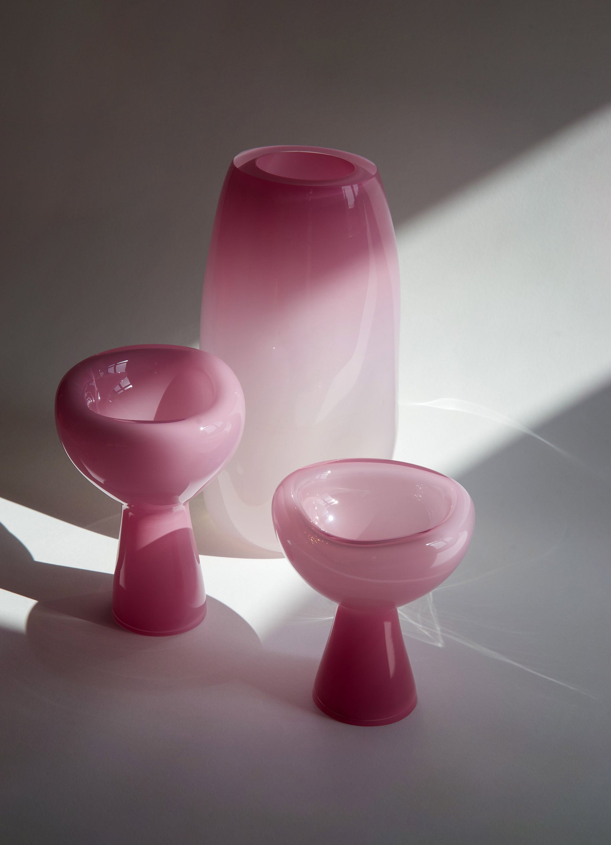 Set of three pink glass pieces on a light surface with a soft shadow