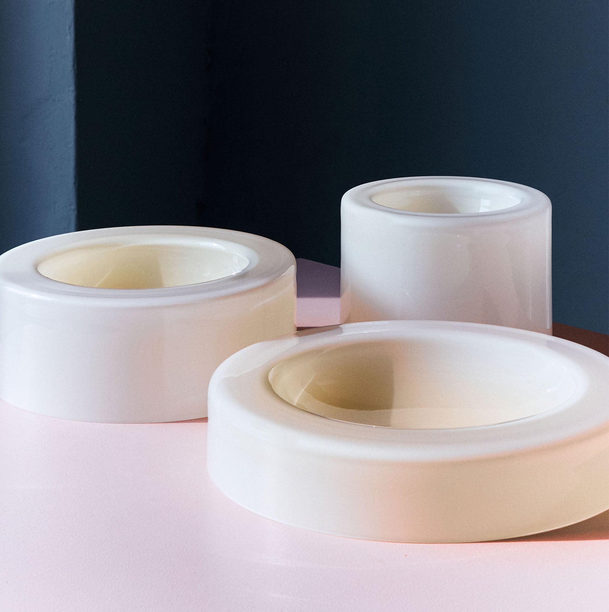 Three cylindrical vanilla bowls of various heights and widths are placed on a pink and blue gradient background