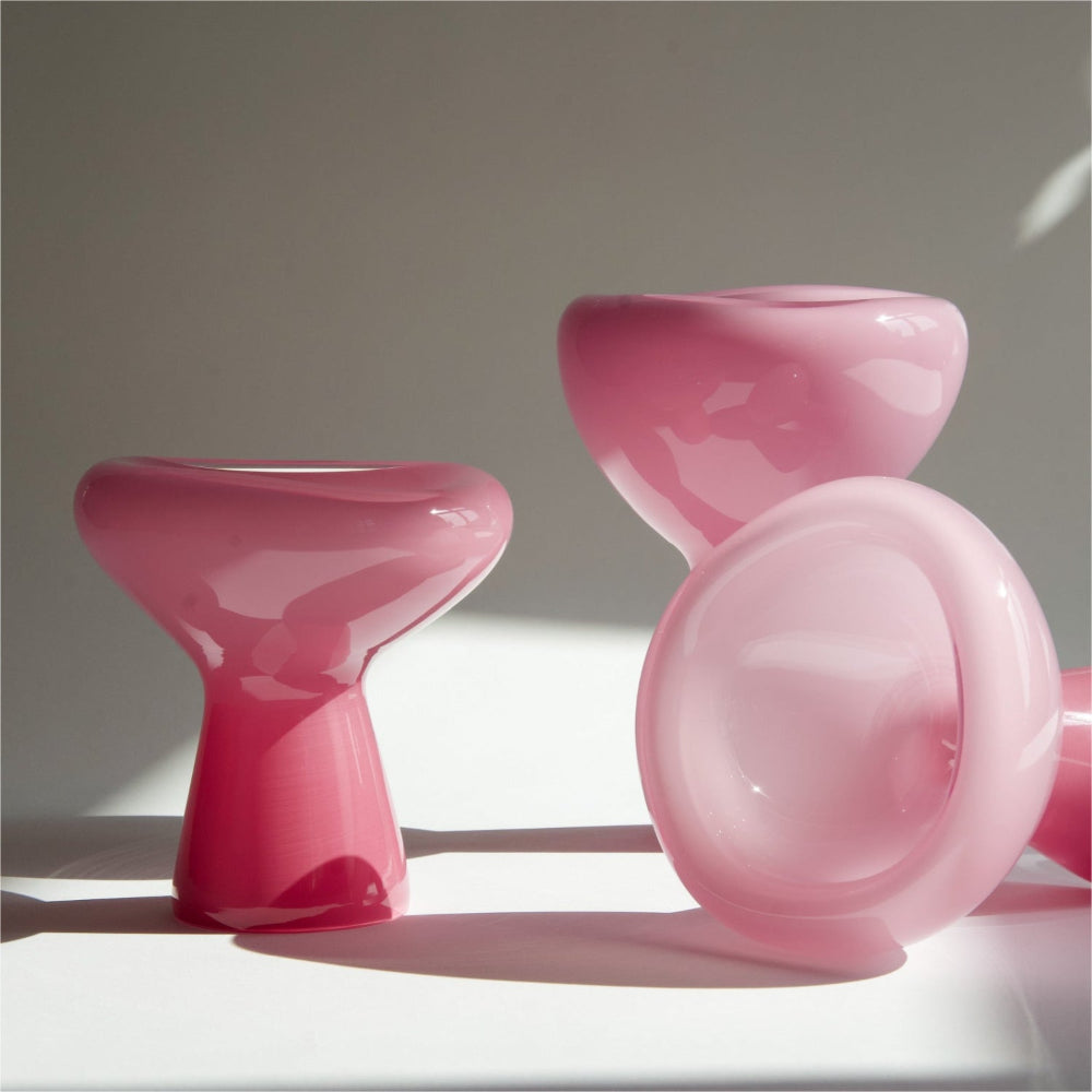 Set of pink plastic chairs on a white surface with a neutral background