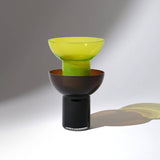 Two Plash glasses stacked on top of each other photographed on a white surface with a gray background and soft shadows.