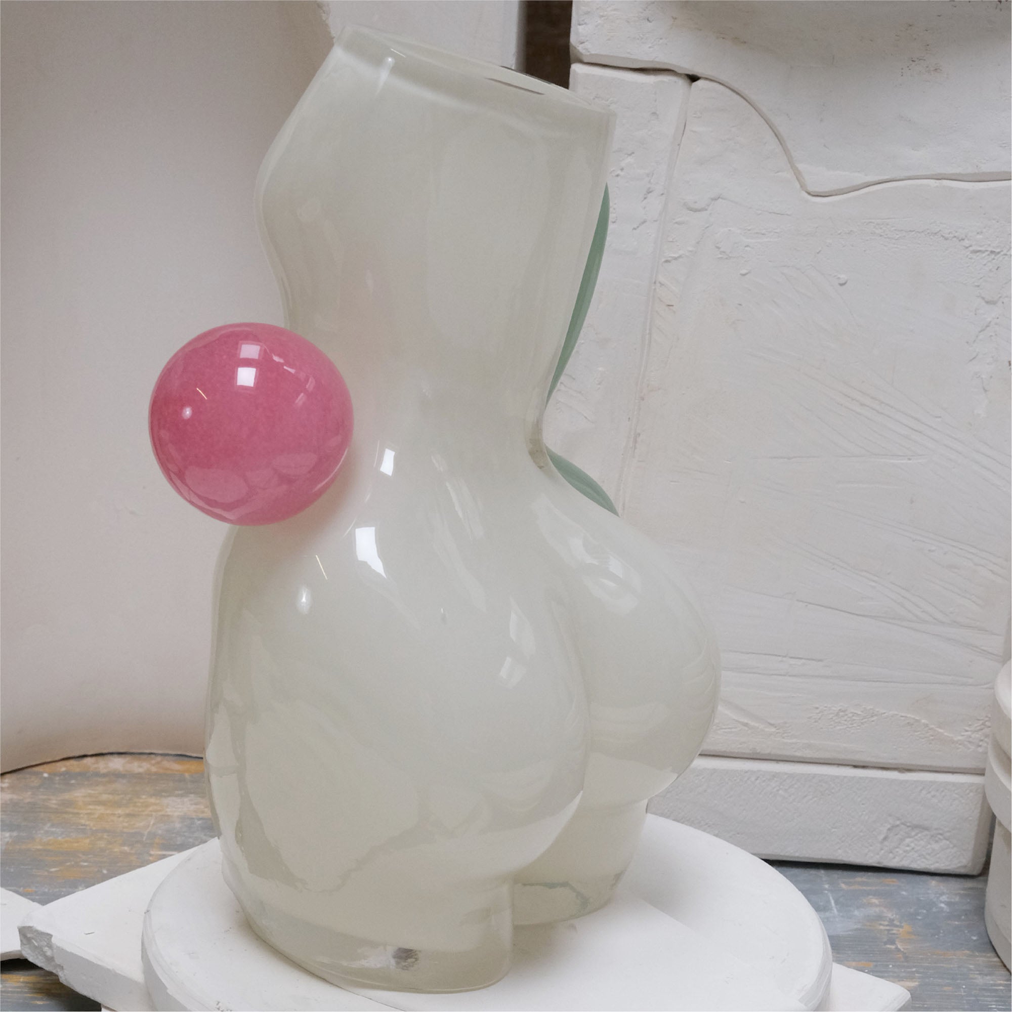 White womans figure made of glass with pink ball on the waist, in a workshop setting