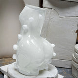 White ceramic vase with decorative elements in a workshop like surrounding