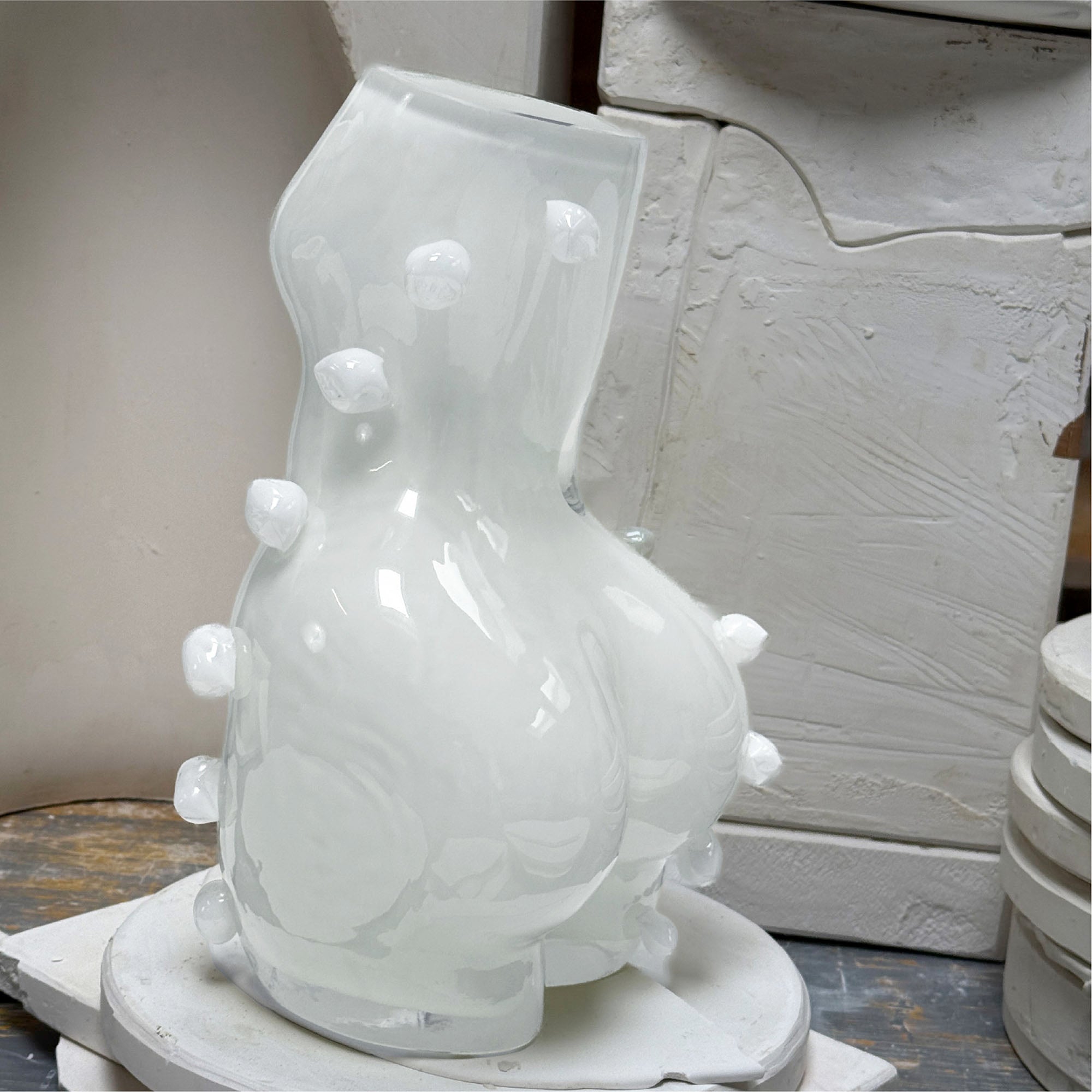 White ceramic vase with decorative elements in a workshop like surrounding