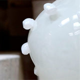 Close-up of a white glass vase with bulbous design on a dark background