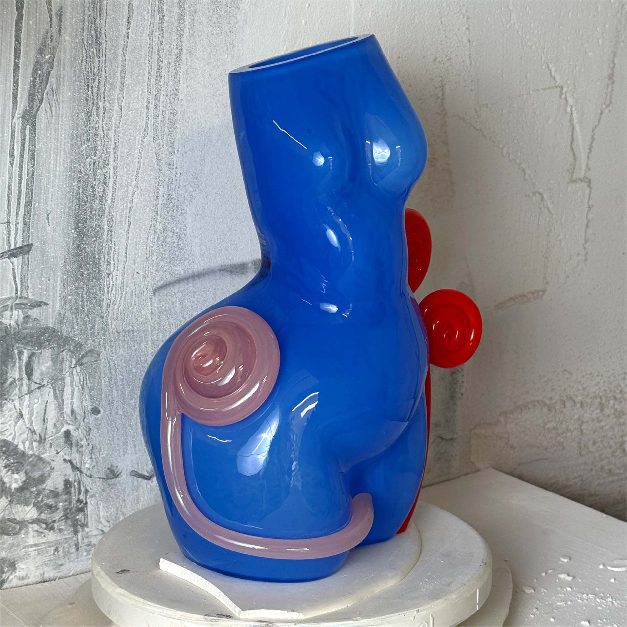Blue abstract sculpture with pink and red accents on a white surface