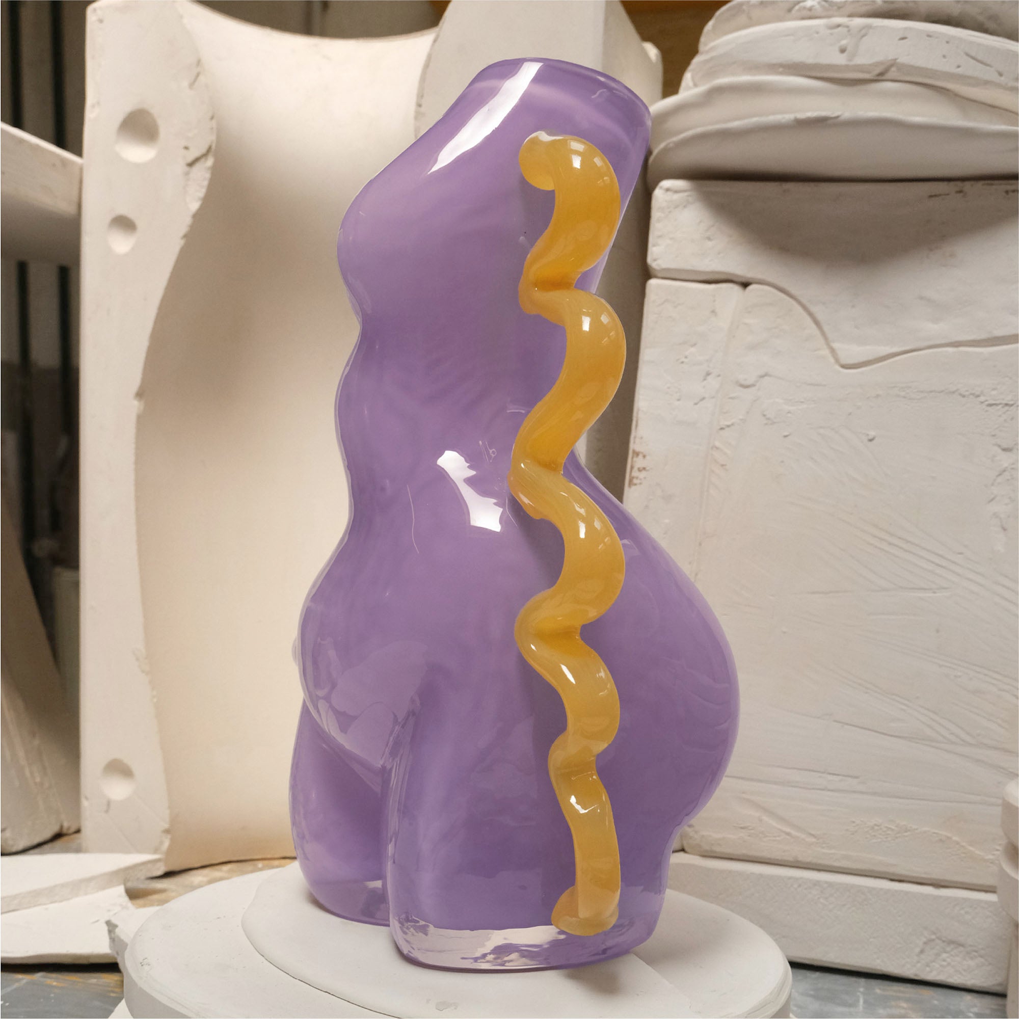 Purple glass sculpture with wavy orange accent in a workshop setting