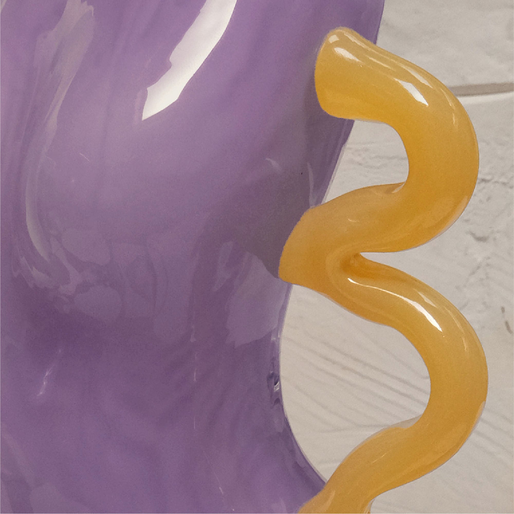 Closeup of the yellow wavy object against the purple glass body of the figure on a textured background