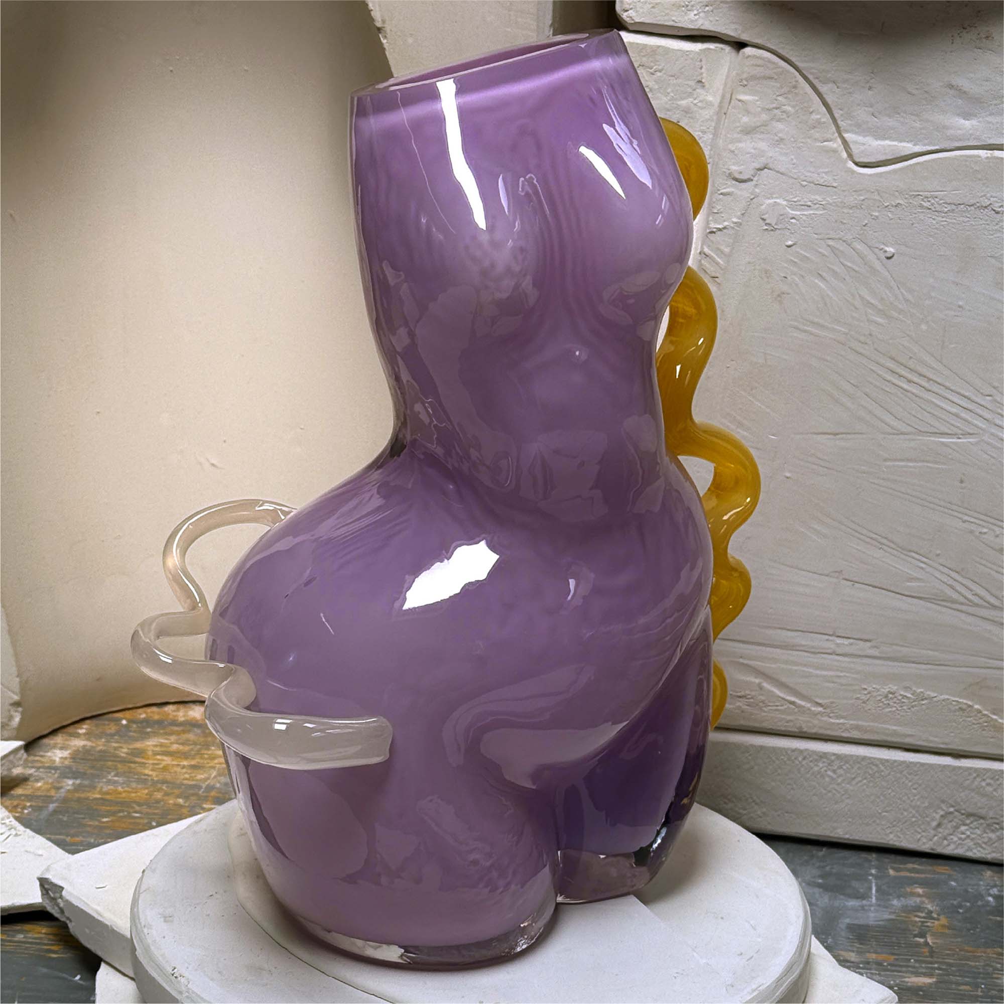 Purple glass vase with a textured surface on a white surface.