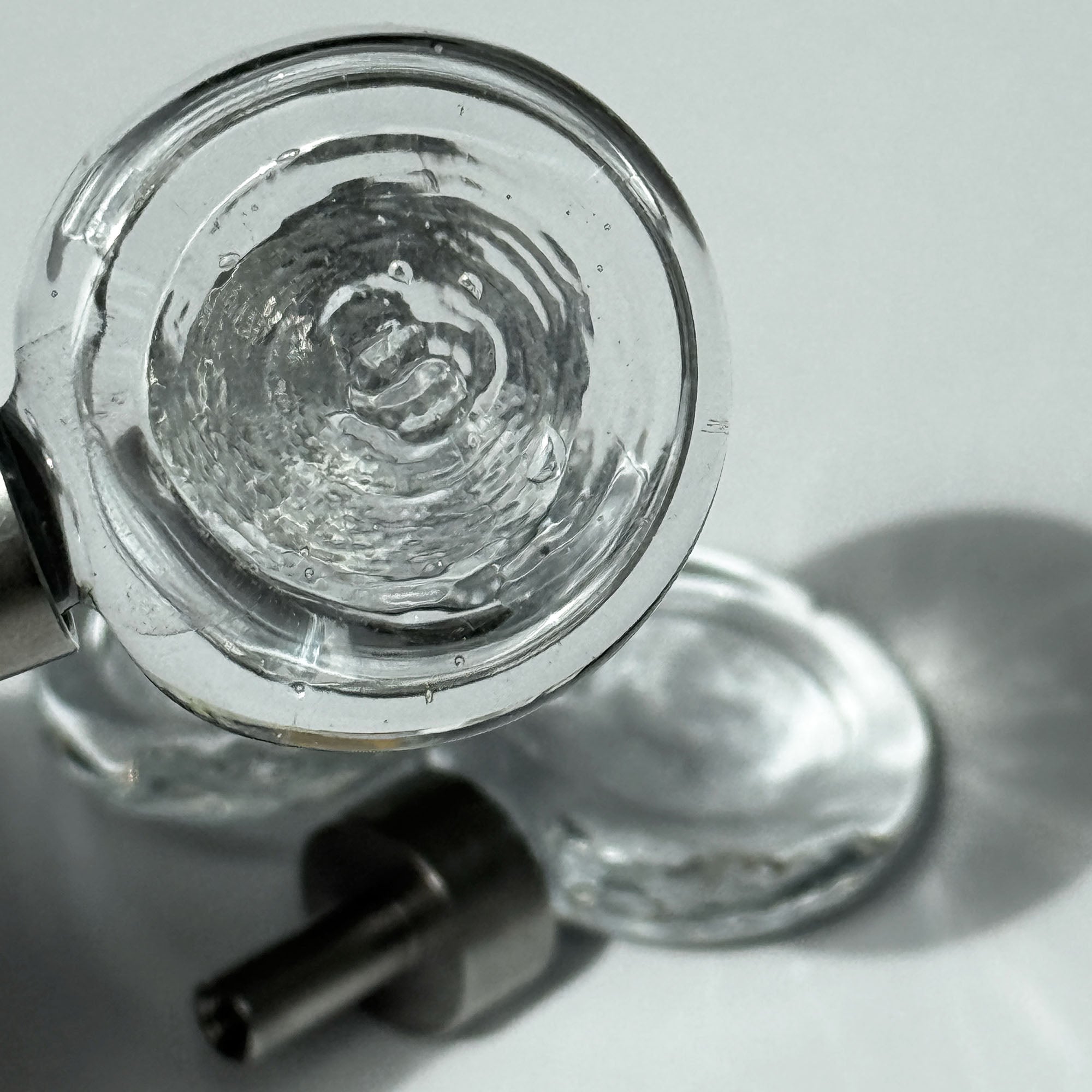 Close up of the flux knob, with beautiful light and another flux knob visible in the background laying on a white surface and light shining through it.