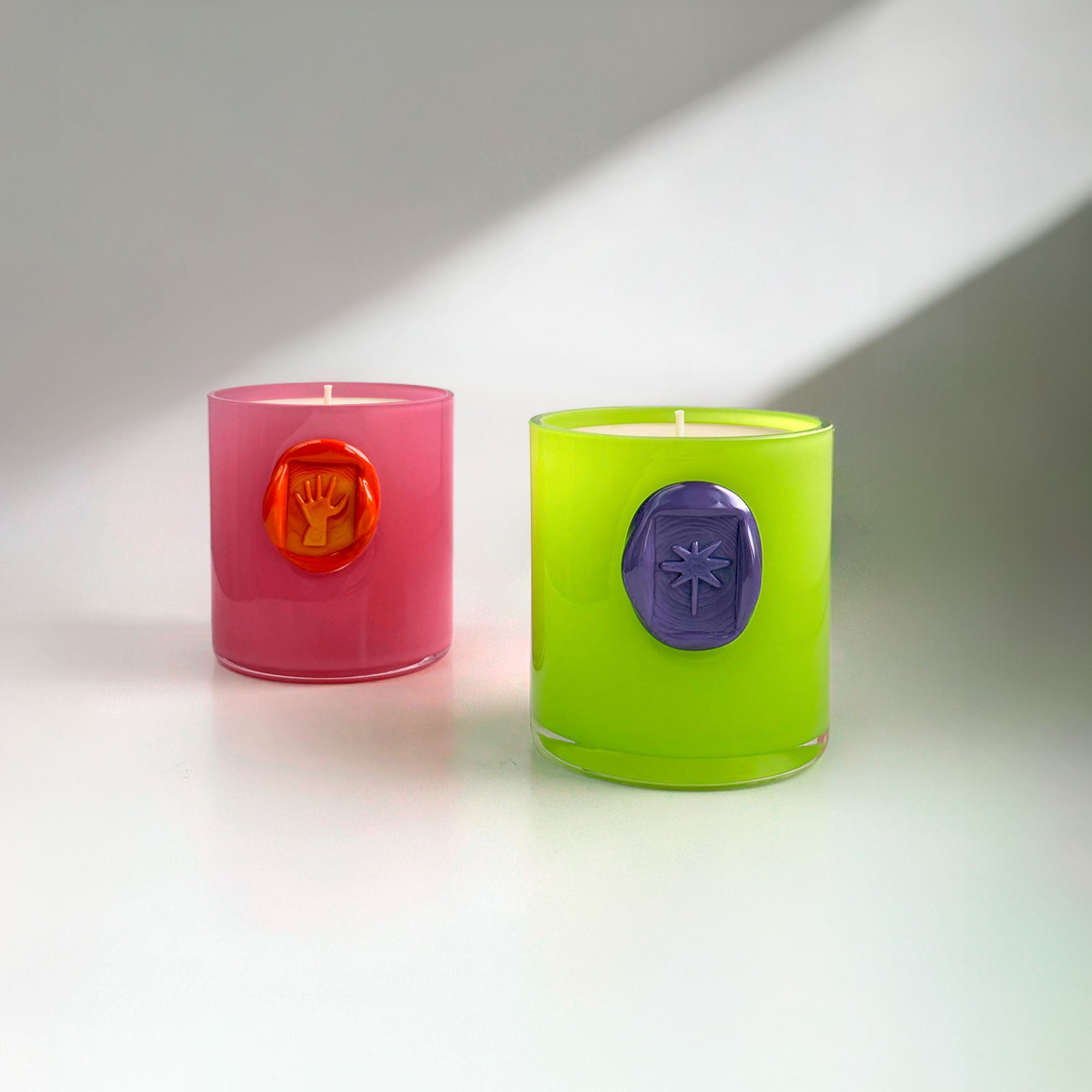 Two colorful candles with decorative seals on a neutral background