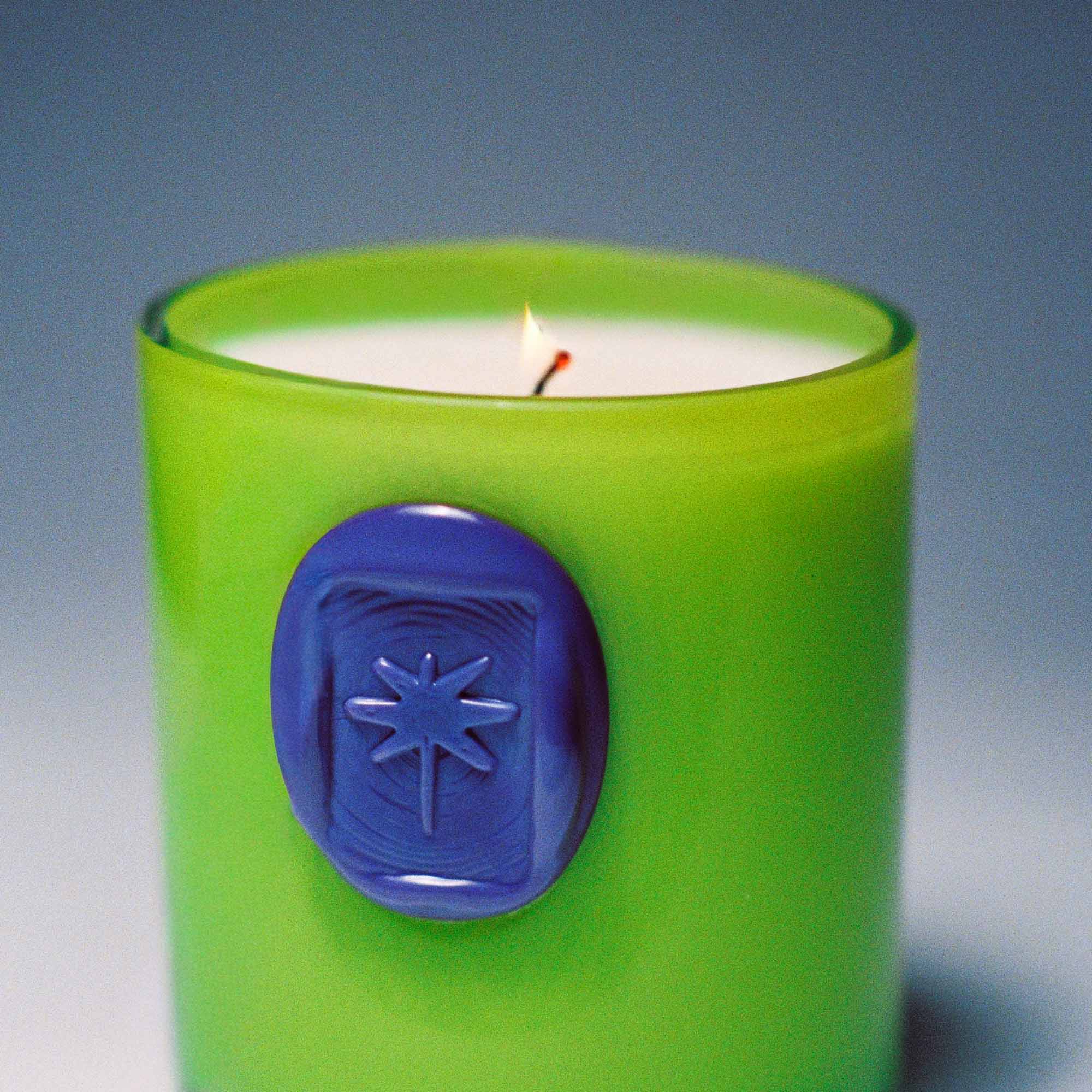 Green candle with a purple imprint seal on a gradient background