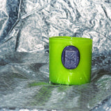 Green candle with a purple imprint seal on a textured silver background