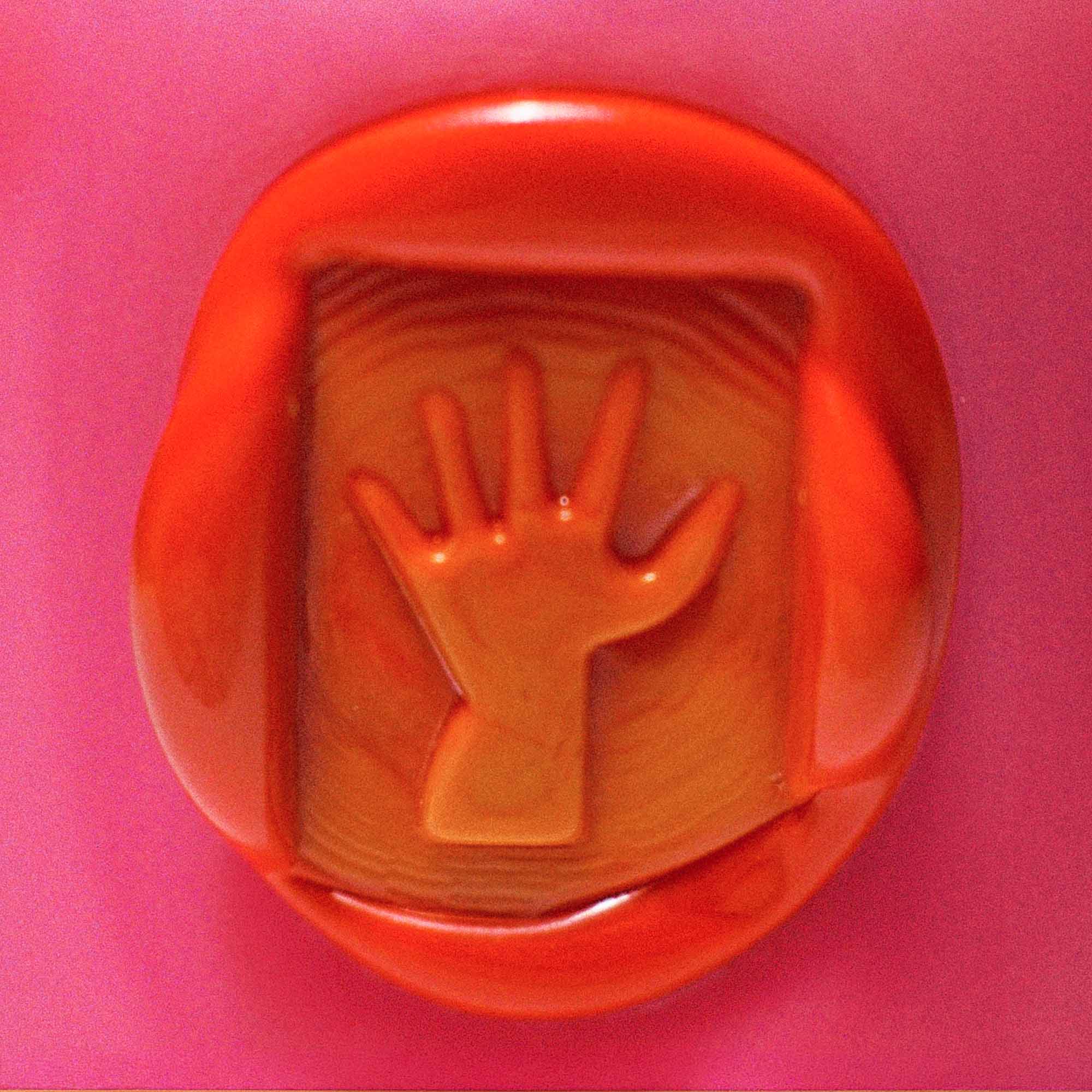 Handprint impression in a red seal imprint on a pink glass background