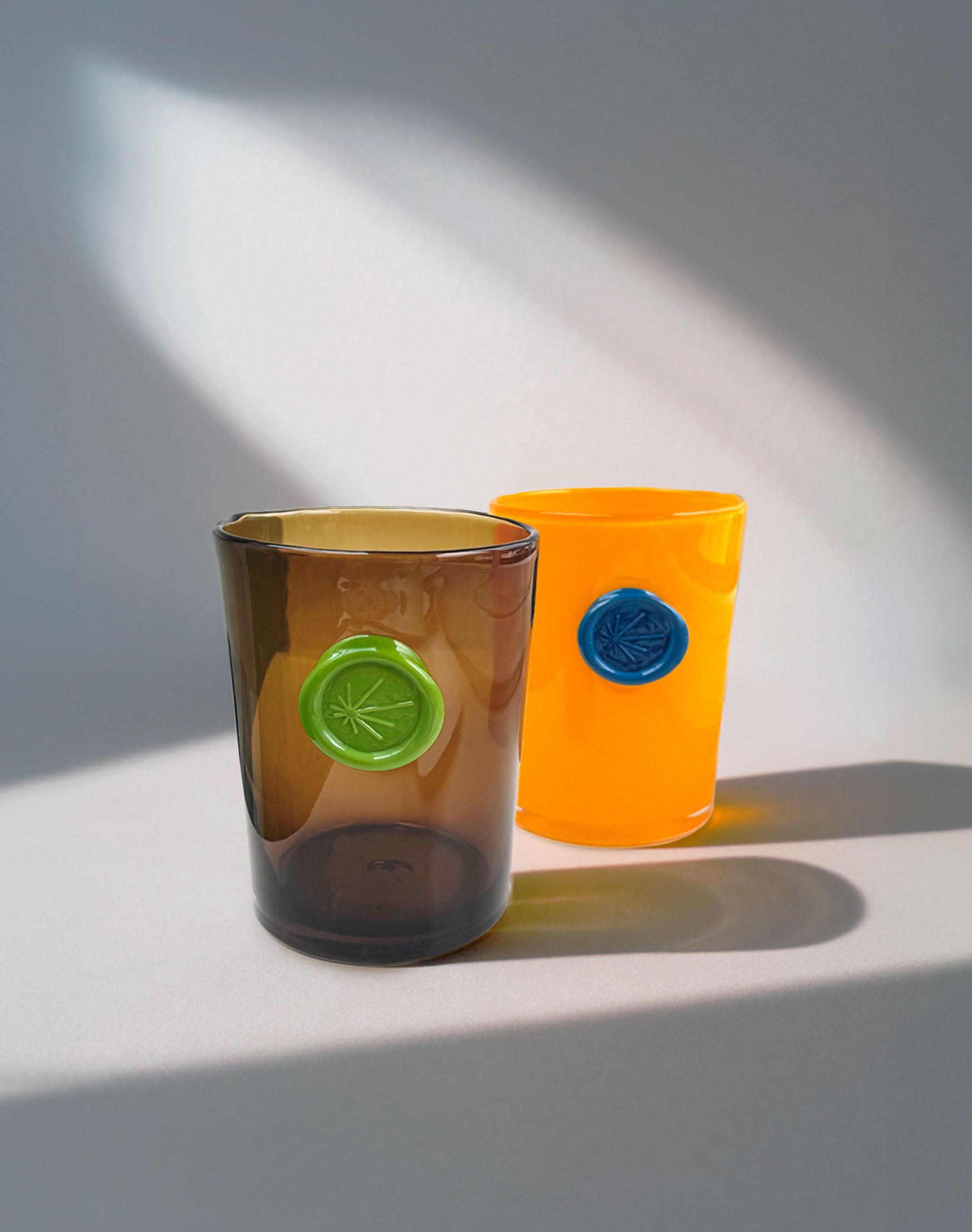 Two glass vases with decorative imprints on a light surface with shadows