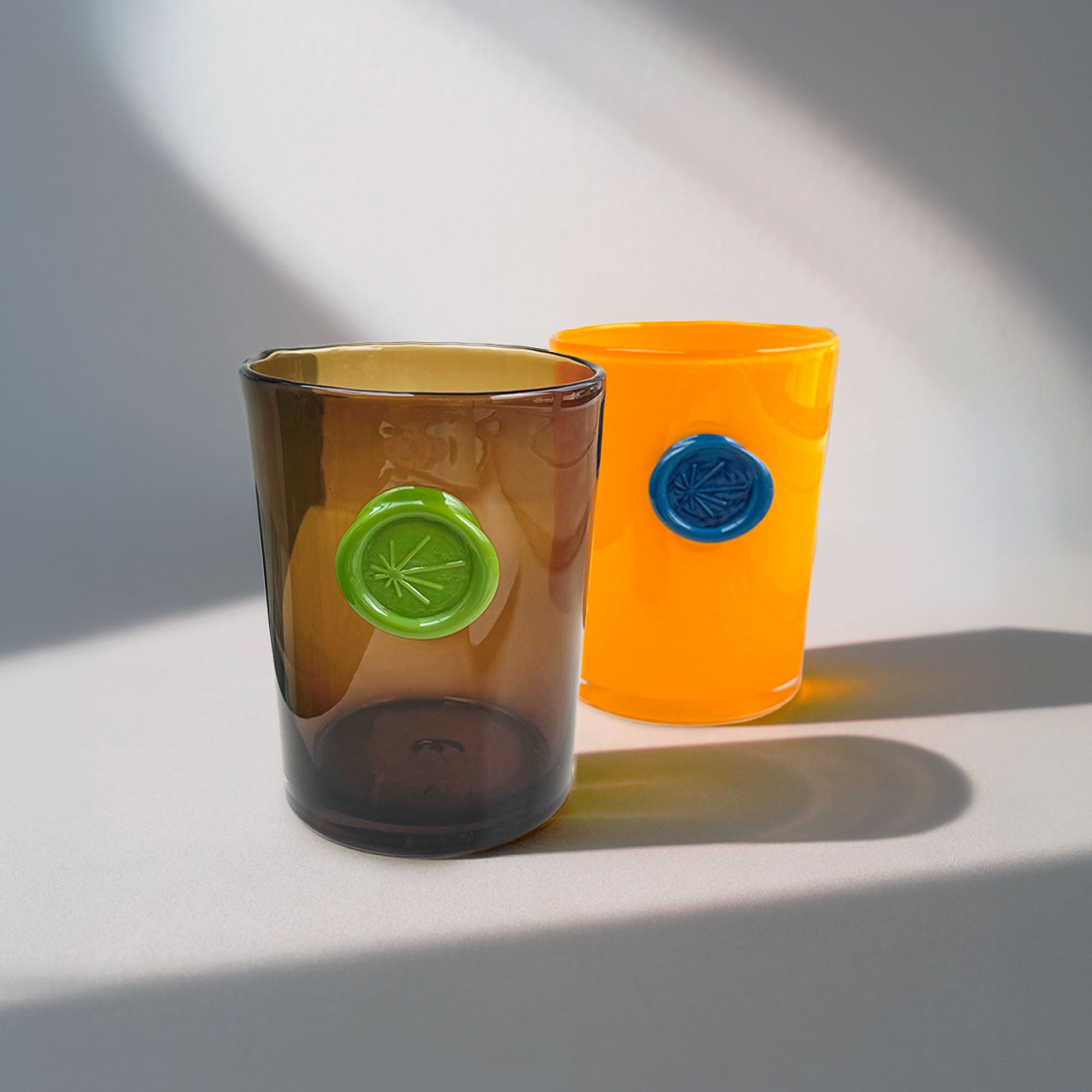 Two colored vases with circular imprint designs stamped on front of each, on a light background.