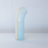 Soft blue nessie with a vanilla stripe on the back, curved object, on a light gray background, facing away from the camera to see the back view of Nessie.
