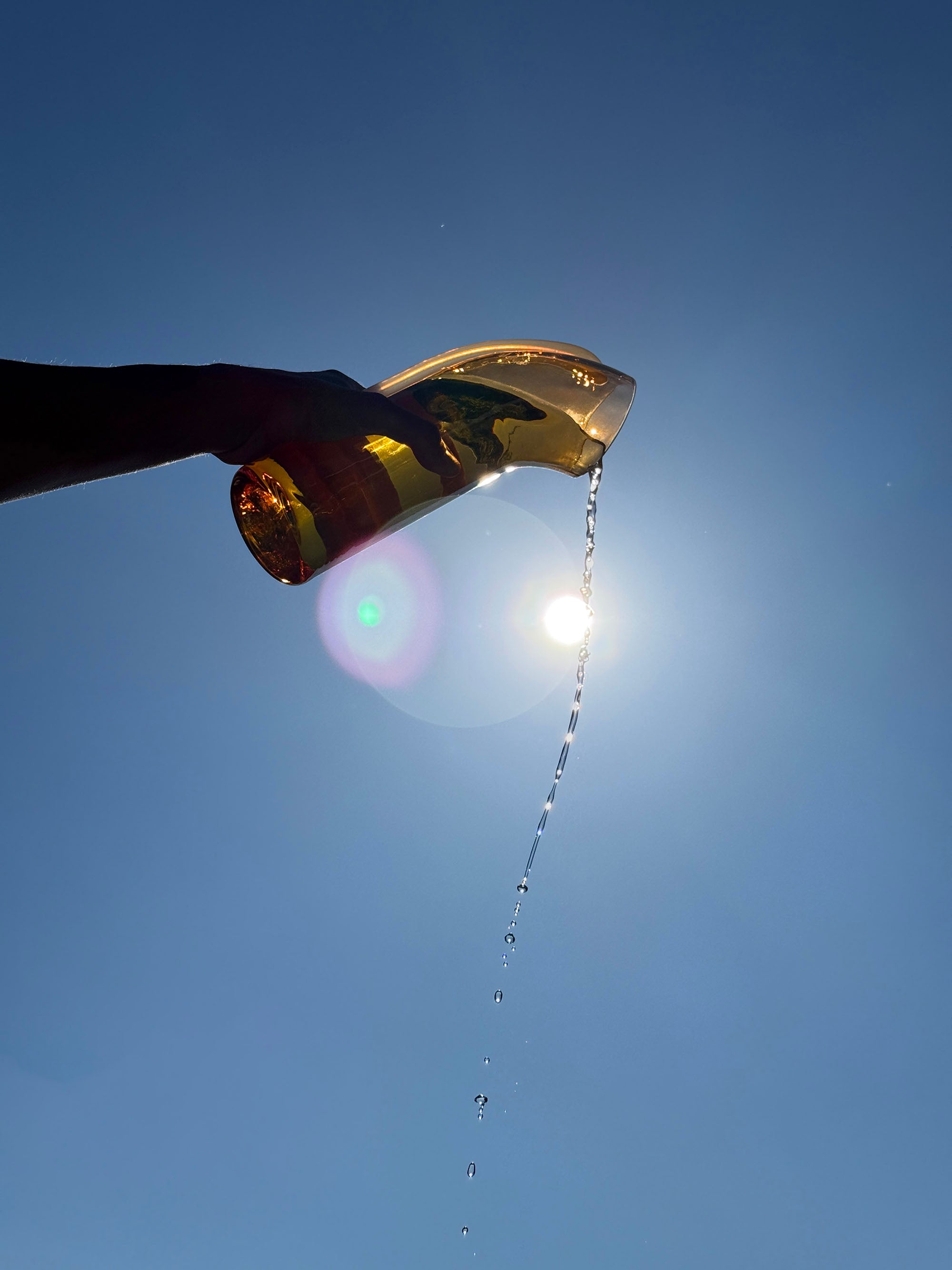 Nessie carafe being tilted to pour liquid against a clear blue sky