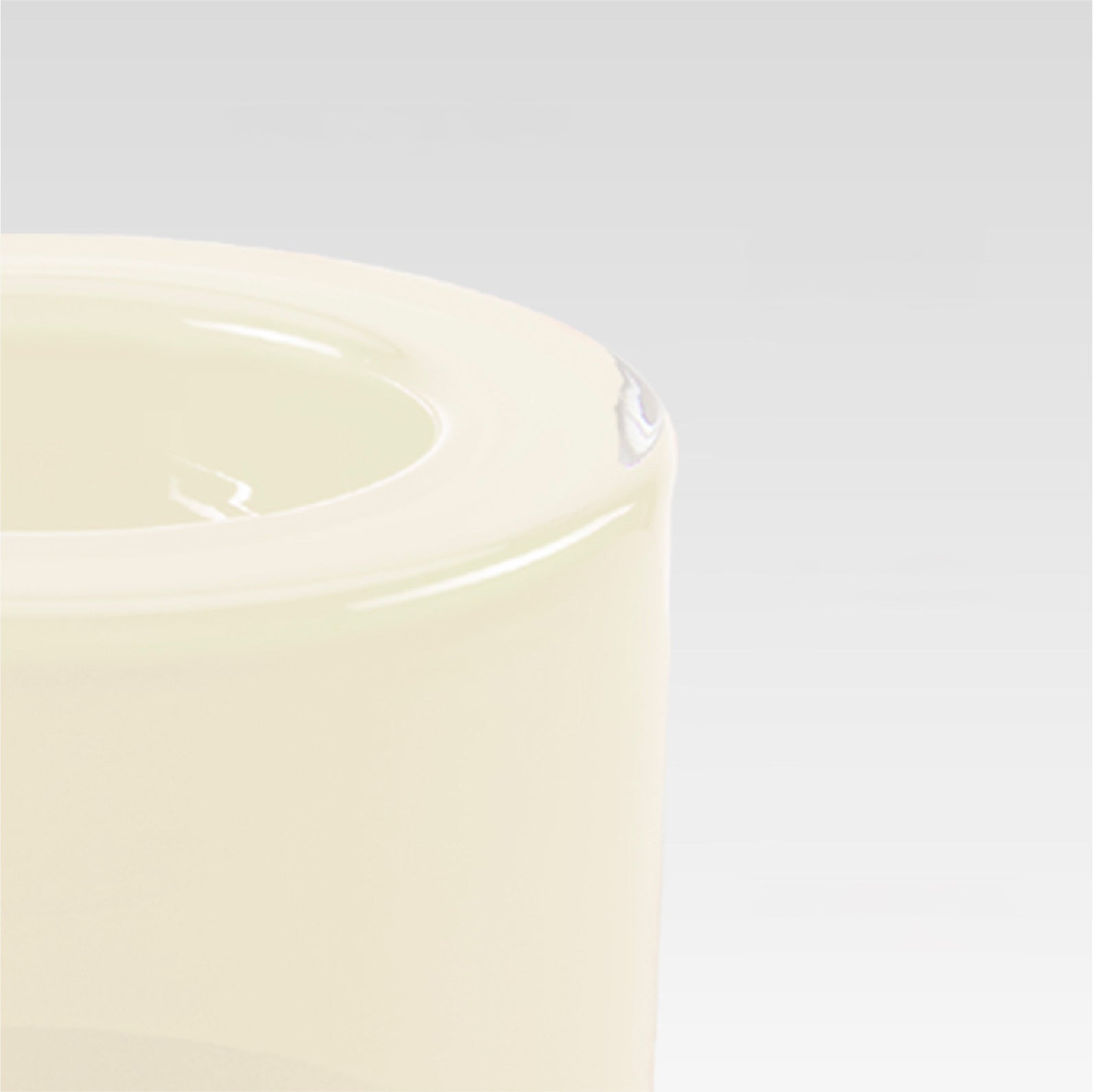 Close-up of the corner of a smooth vanilla white bowl on a light gray background