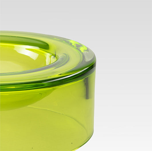 Close-up of a translucent lime green wetbowl showing the thick rim and smooth curved glass against a light gray background.