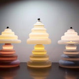 Three unique Pulsar Lamps positioned on a table with the tall vanilla lamp in the centre. On a  reflective surface with a moody atmosphere.