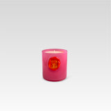 Pink candle with a red imprint stamp on the front that has a shape of a hand inside it, on a light gray background