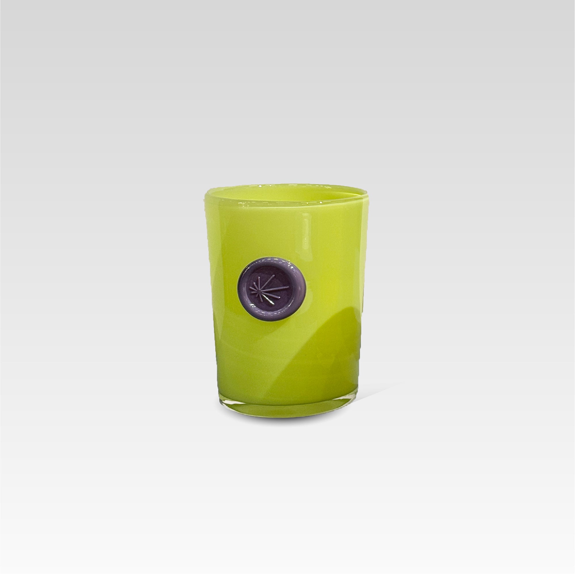 Green glass candle holder with a purple imprint stamp on a white background