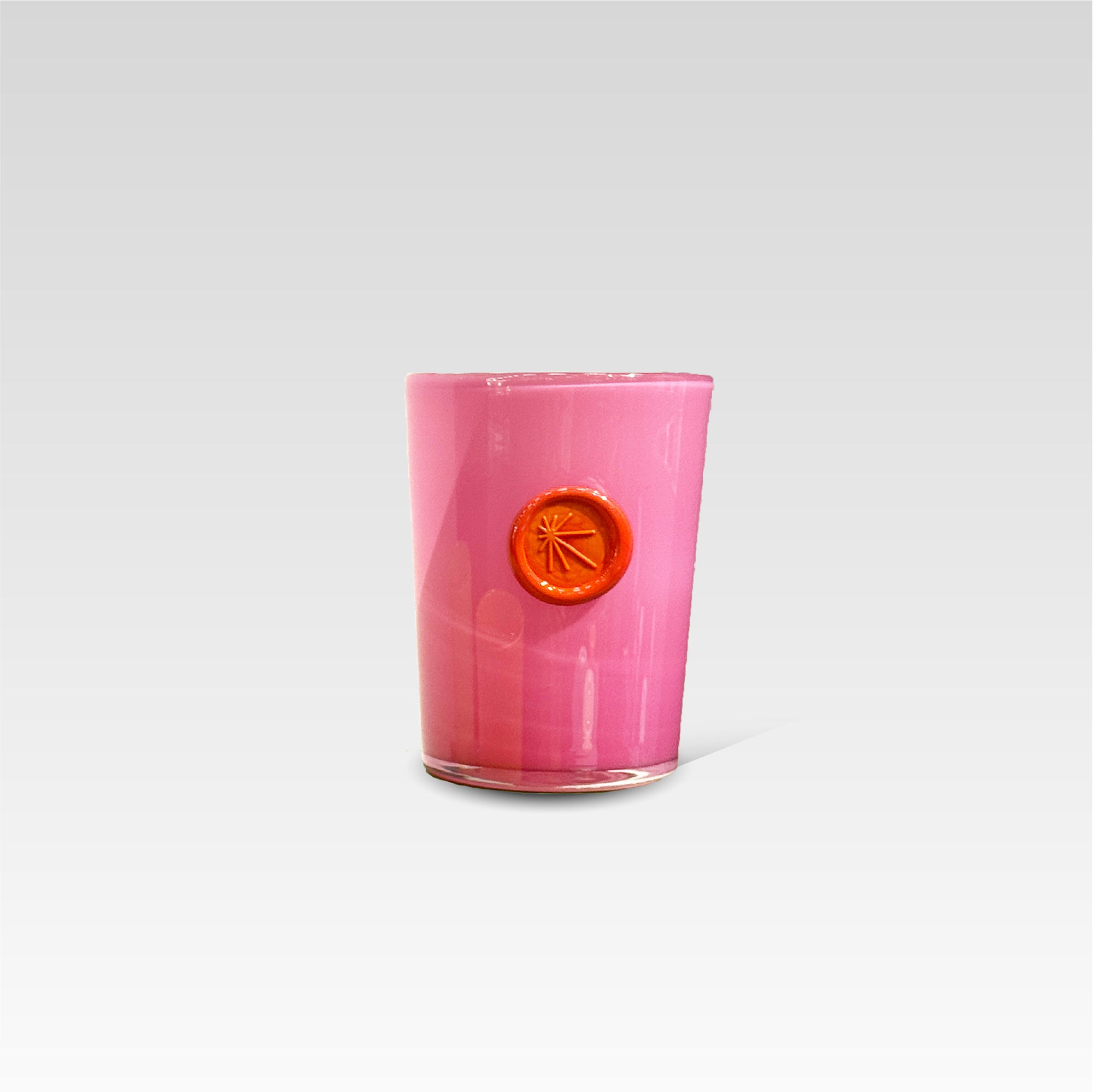 Pink candle with an orange imprint in the middle of it, on a white background