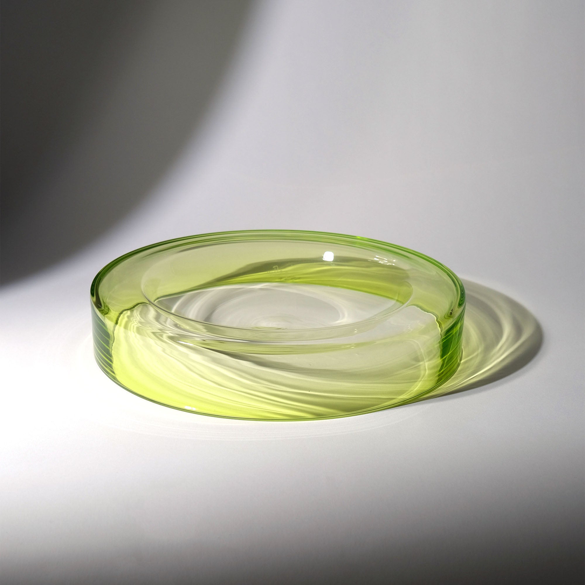A translucent light green wetbowl glass, photographed on a white surface with a soft shadow.