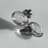 Close-up of two flux cabinet knobs with metallic fixings on a light background.