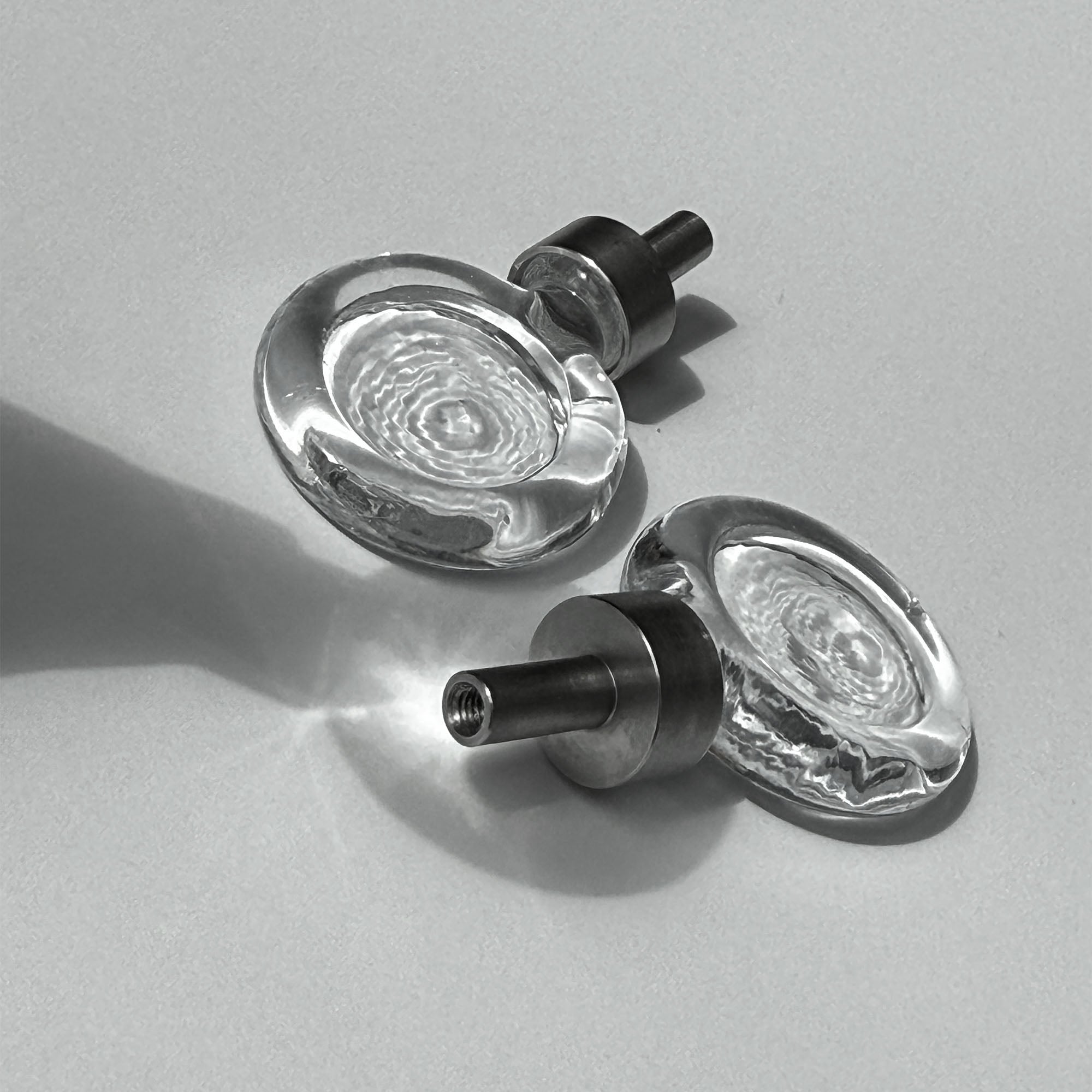 Close-up of two flux cabinet knobs with metallic fixings on a light background.
