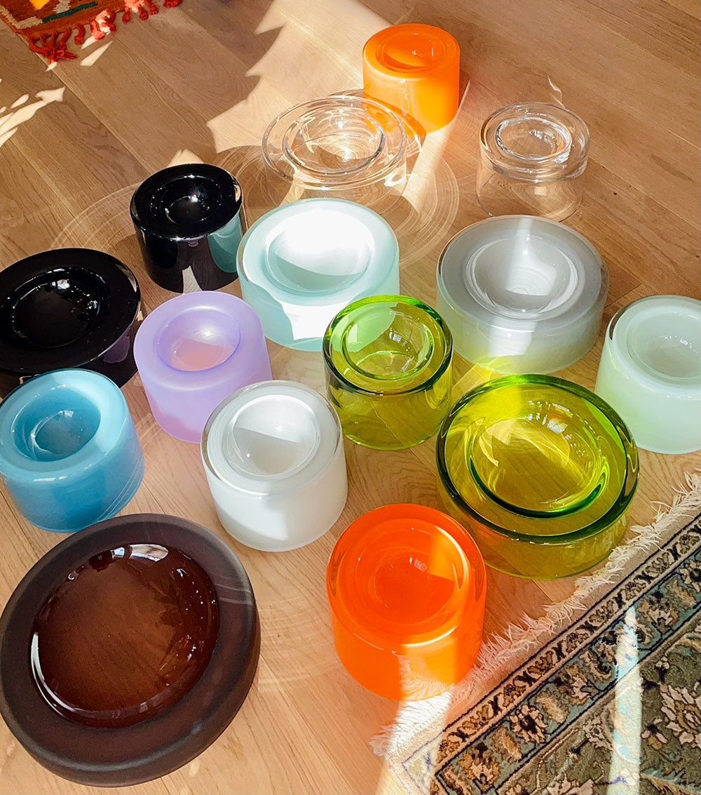 Colorful glass wetbowls on a wooden surface with sunlight shining through and carpet pieces appearing in the image