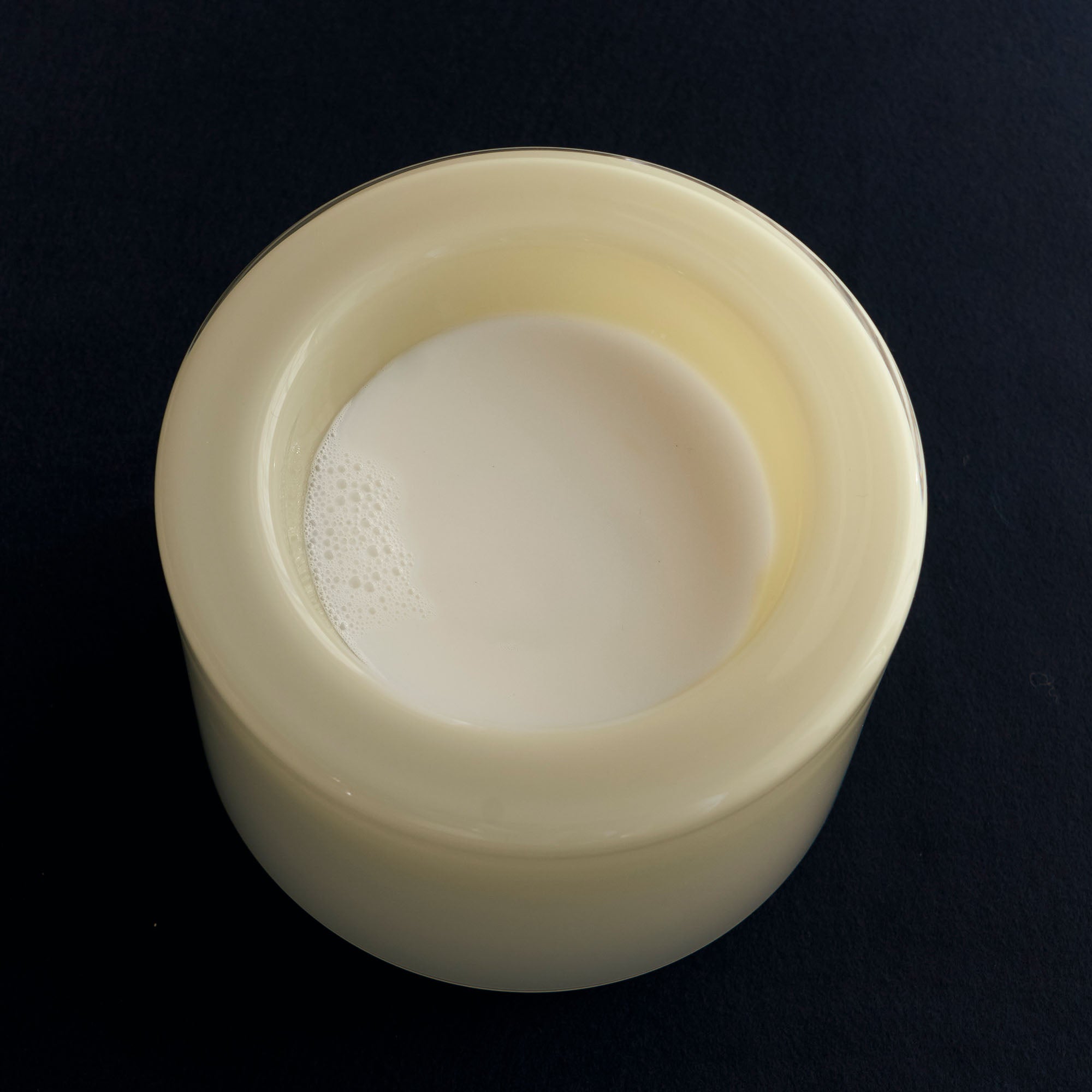 High vanilla bowl, filled with milk on a black background