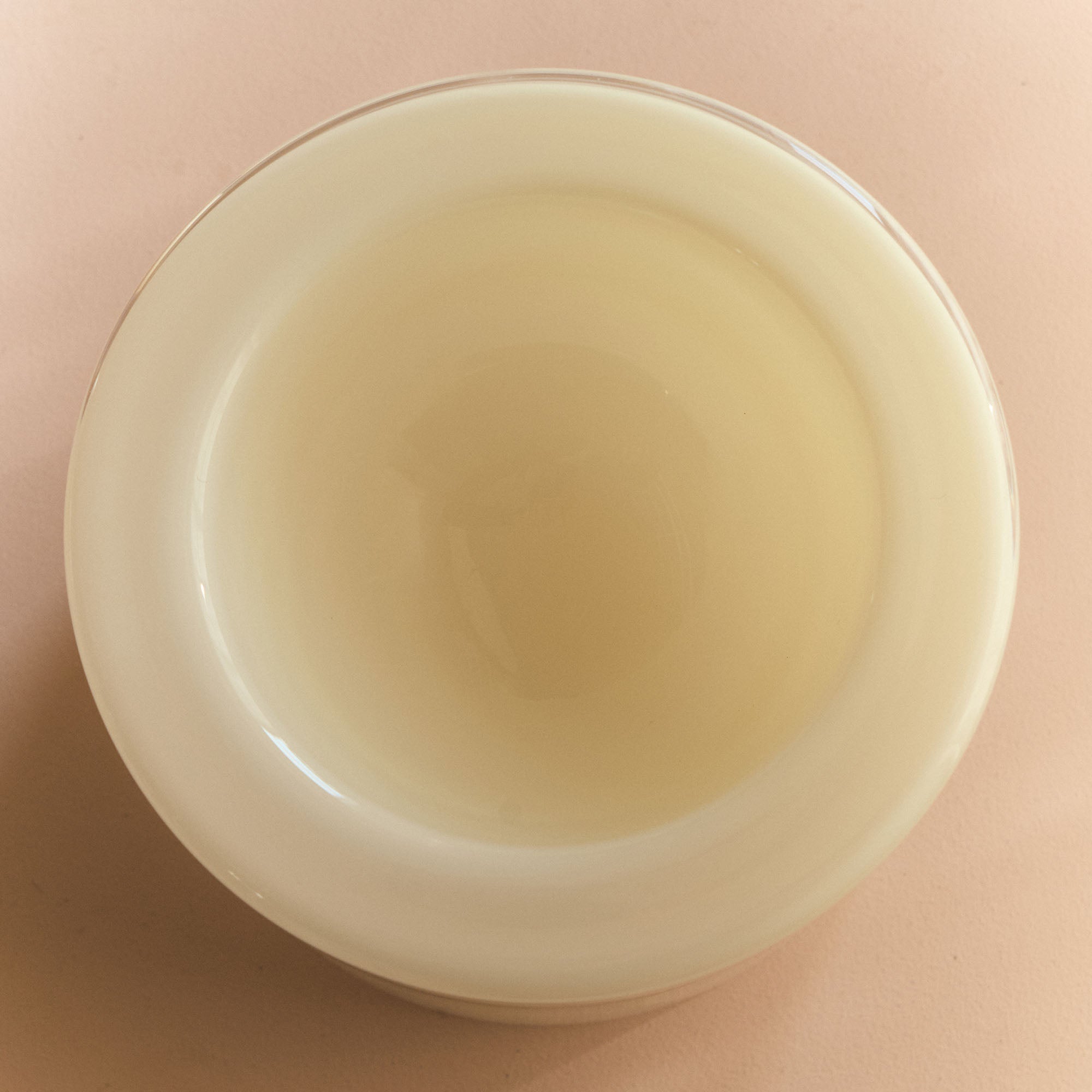 White vanilla bowl, top view, on a beige-pink background