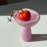 Red tomato on a pink stand with a white background