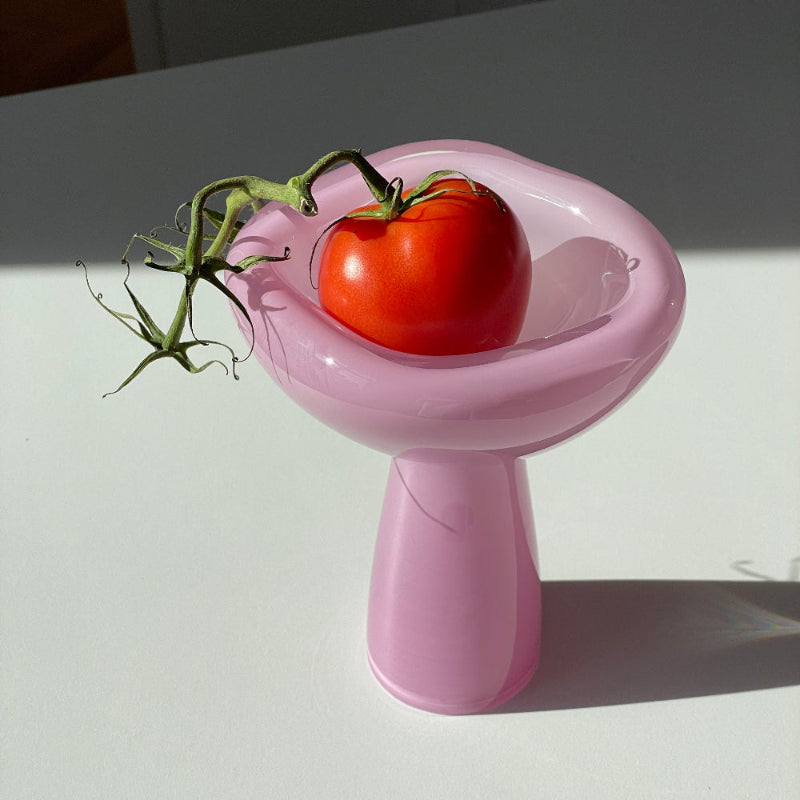 Red tomato on a pink stand with a white background